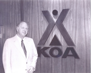 Kampgrounds of America Inc. founder Dave Drum in front of the iconic KOA logo in 1964.